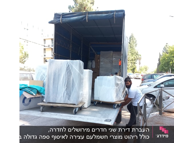 אדם מעמיס משטחים עטופים למשאית הובלה
